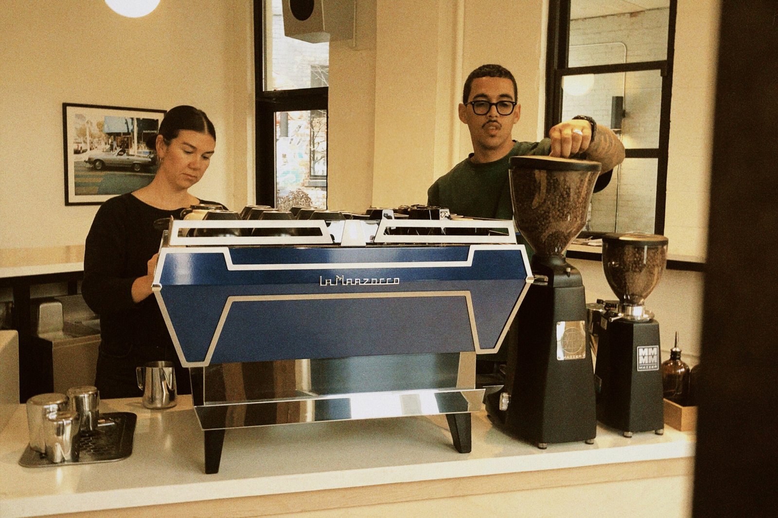 Baristas behind the blue La Marzocco espresso machine at La Ventana Cafe